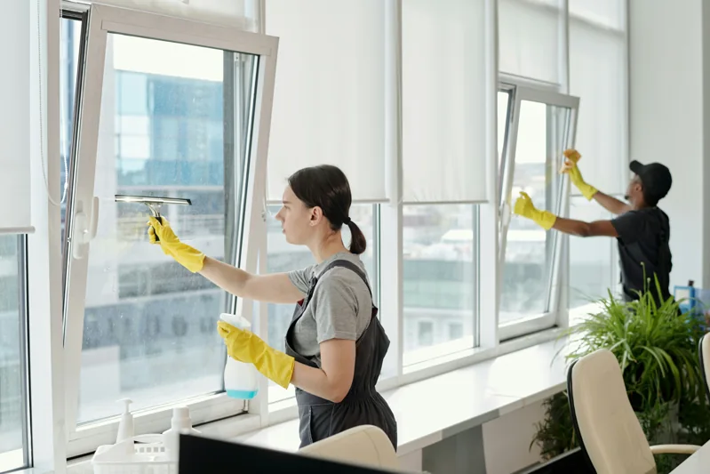 Professional cleaners carefully working on bright office windows