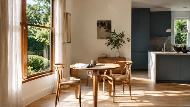 A sunlit dining table beside a blue kitchen.